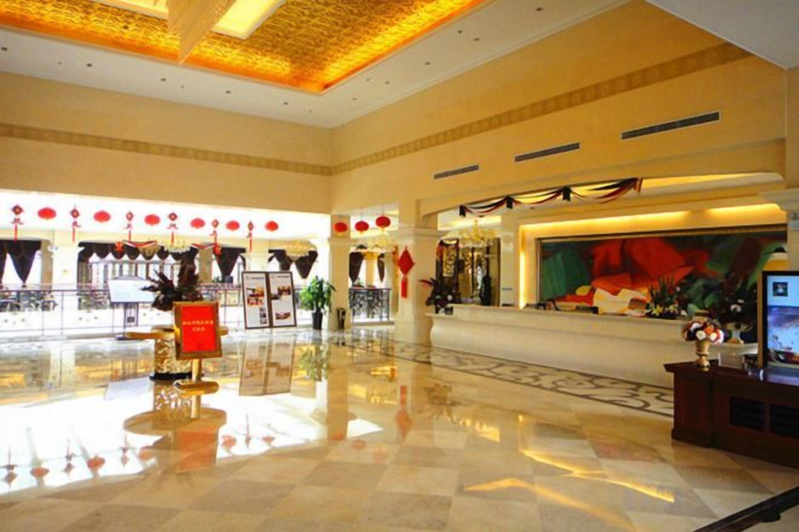 A spacious lobby with a polished floor, a reception desk, and a large wall mural.