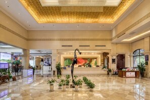 A spacious lobby with a high ceiling, a reception desk, and potted plants. - Nanshan Xingmao Hotel & Resort (Lu'an)