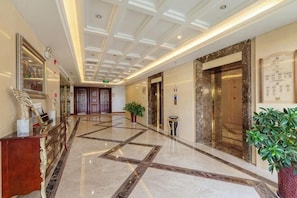 A hotel lobby with a marble floor, elevators, a reception desk, and a potted plant. - Nanshan Xingmao Hotel & Resort (Lu'an)
