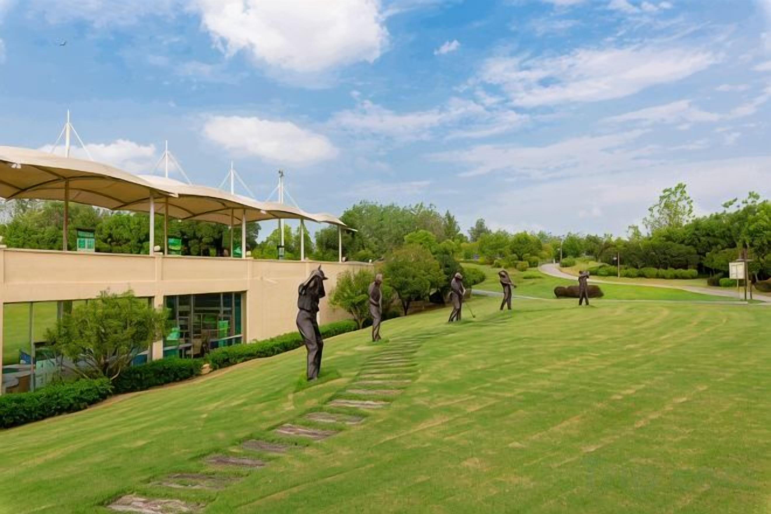 Een golfbaan met een gebouw, voorzien van een overdekte gang en een heldere lucht.