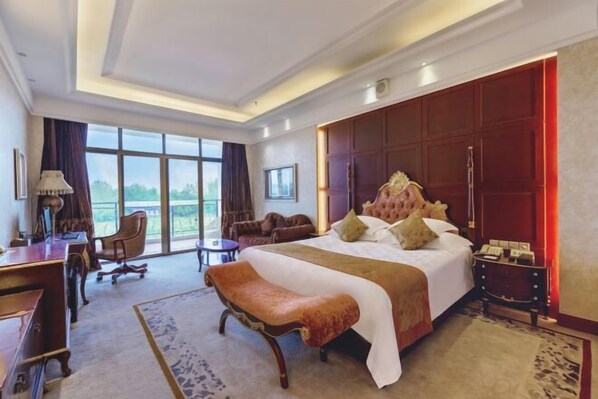 Habitación de hotel con una cama grande, un escritorio, una silla y vistas al exterior.