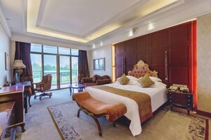 Habitación de hotel con una cama grande, un escritorio, una silla y vistas al exterior.