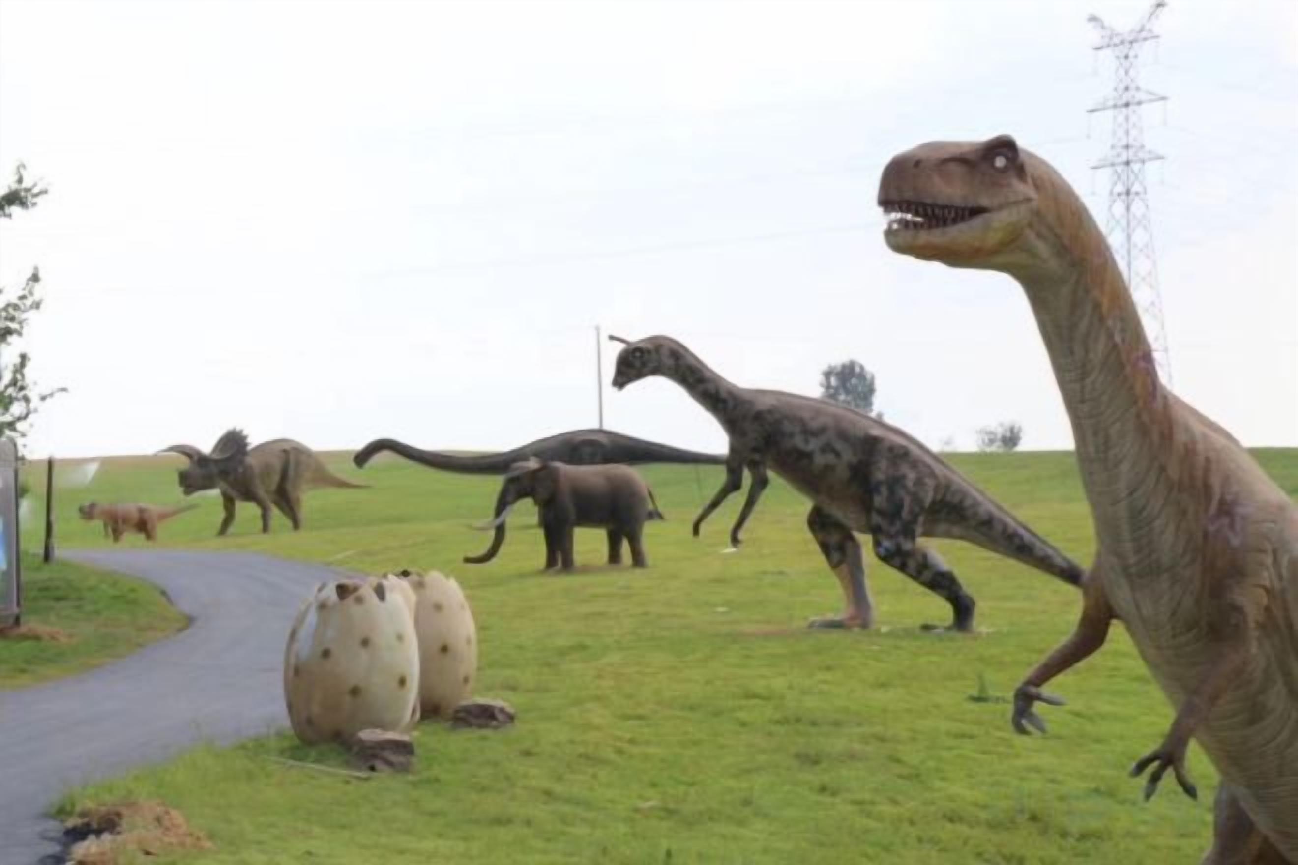 Een grasveld met verschillende dinosaurusbeeldhouwings.