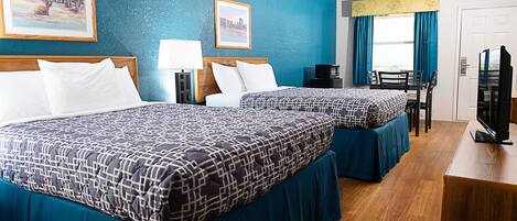 A hotel room with two beds, a desk, a chair, a television, and artwork on the walls.
