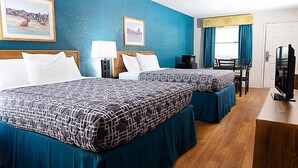 A hotel room with two beds, a desk, a chair, a television, and artwork on the walls.