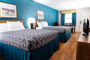 A hotel room with two beds, a desk, a chair, a television, and artwork on the walls.