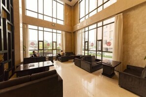 A spacious lobby with high ceilings, large windows, and modern furniture. - Binfen Grand Hotel (Wuhu)