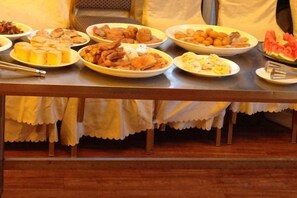 Una mesa con diversos alimentos, probablemente para un bufé o comida compartida.