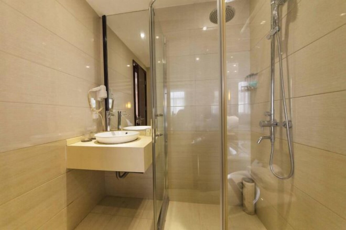 A modern bathroom with a glass-enclosed shower, a sink with a mirror, and a toilet.