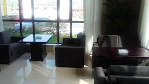 Un hall d’entrée moderne avec une paroi en verre, des sièges confortables et une vue sur l’extérieur.