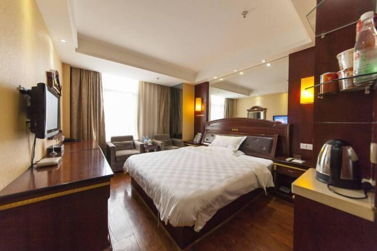 A hotel room with a large bed, a desk with a computer, a chair, and a TV.