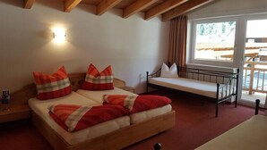 Un dormitorio con una cama de madera, una mesita de noche, un ventanal con cortinas y vistas a una terraza exterior.