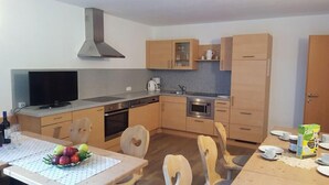 Cocina compacta con estufa, microondas y un ventanal amplio.