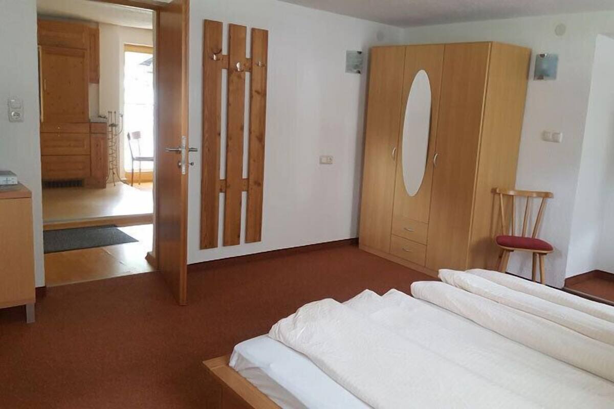 A bedroom with a bed, wooden wardrobe, and a chair.