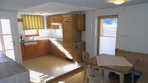 Cocina compacta con armarios de madera, una mesa de comedor con sillas y una ventana que ofrece vistas al exterior.