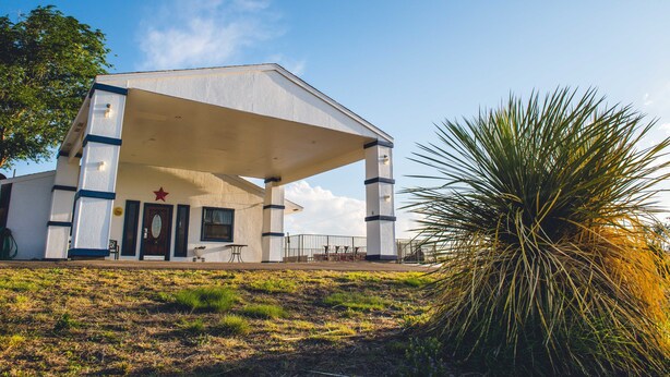 A building with a large overhang, a star on the facade, and a palm tree in the foreground.