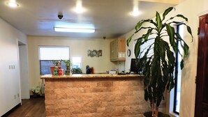 A kitchen with a stone island, wooden flooring, a potted plant, and a window with blinds.