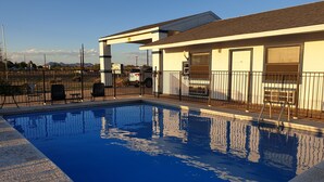 A swimming pool with a clear blue water surface, surrounded by a metal fence.