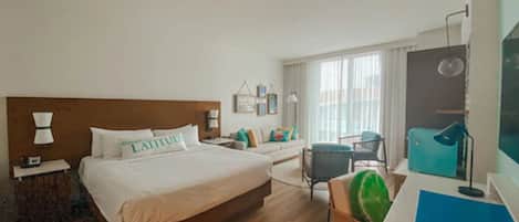 Una habitación de hotel con una cama de madera, un escritorio, una silla y un ventanal con cortinas.
