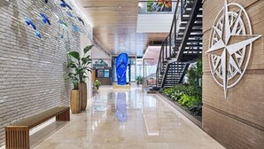 Un hall d’entrée moderne avec un plafond en bois, une grande décoration murale en forme de boussole et une sculpture bleue.