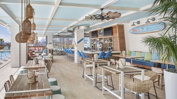 Un bar spacieux avec de hauts plafonds, de nombreux espaces de détente et une vue sur la piscine.