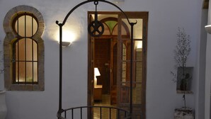 Un edificio tradicional con puerta de madera, portón metálico y planta en maceta.