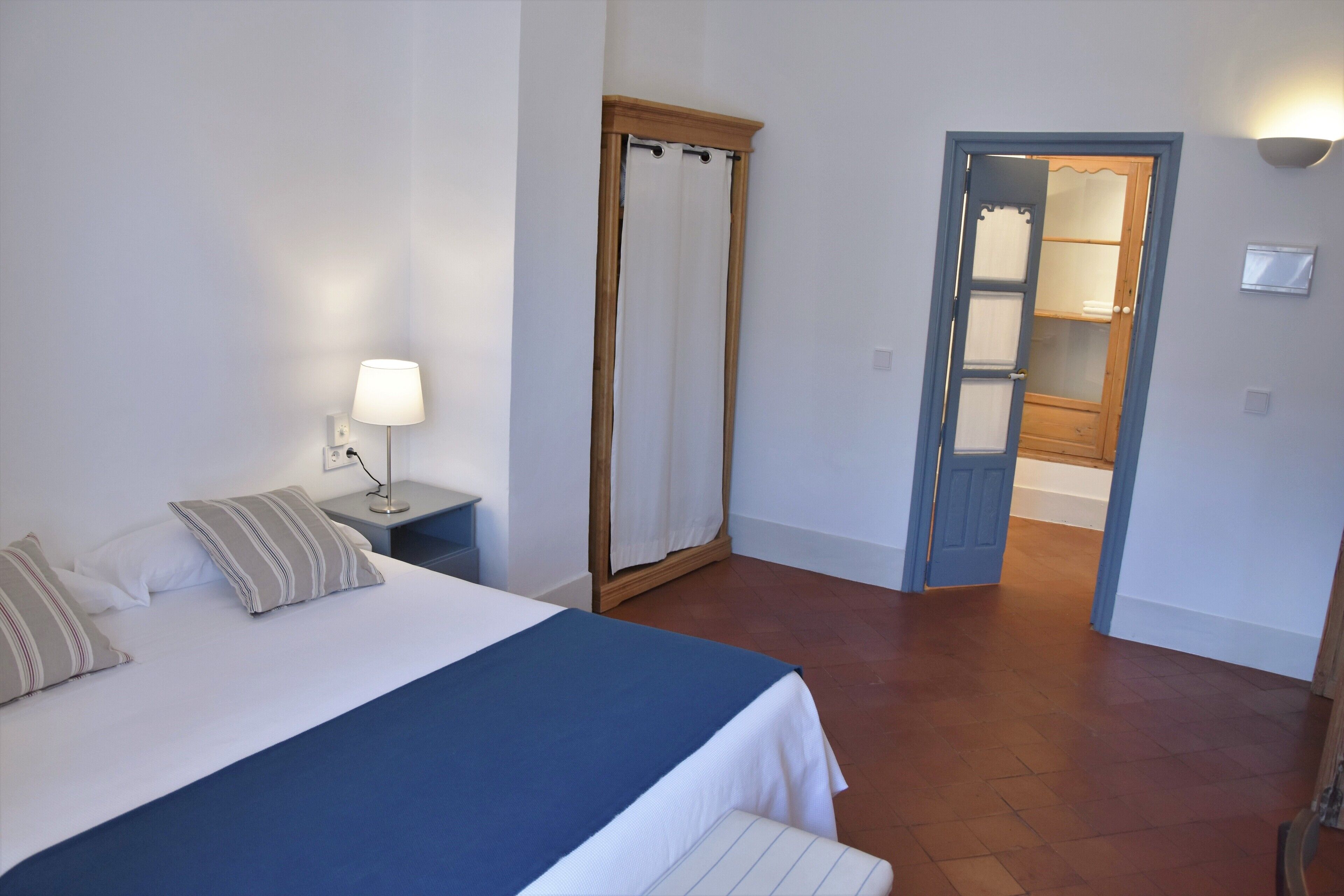 Una camera da letto con un letto, un comodino, una lampada e un armadio.