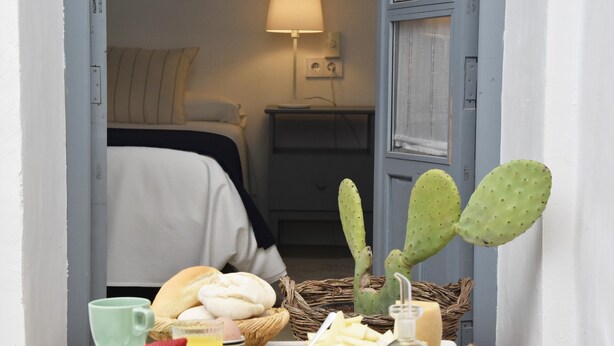 Una mesa de desayuno con un cactus, pan y una botella de aceite de oliva.