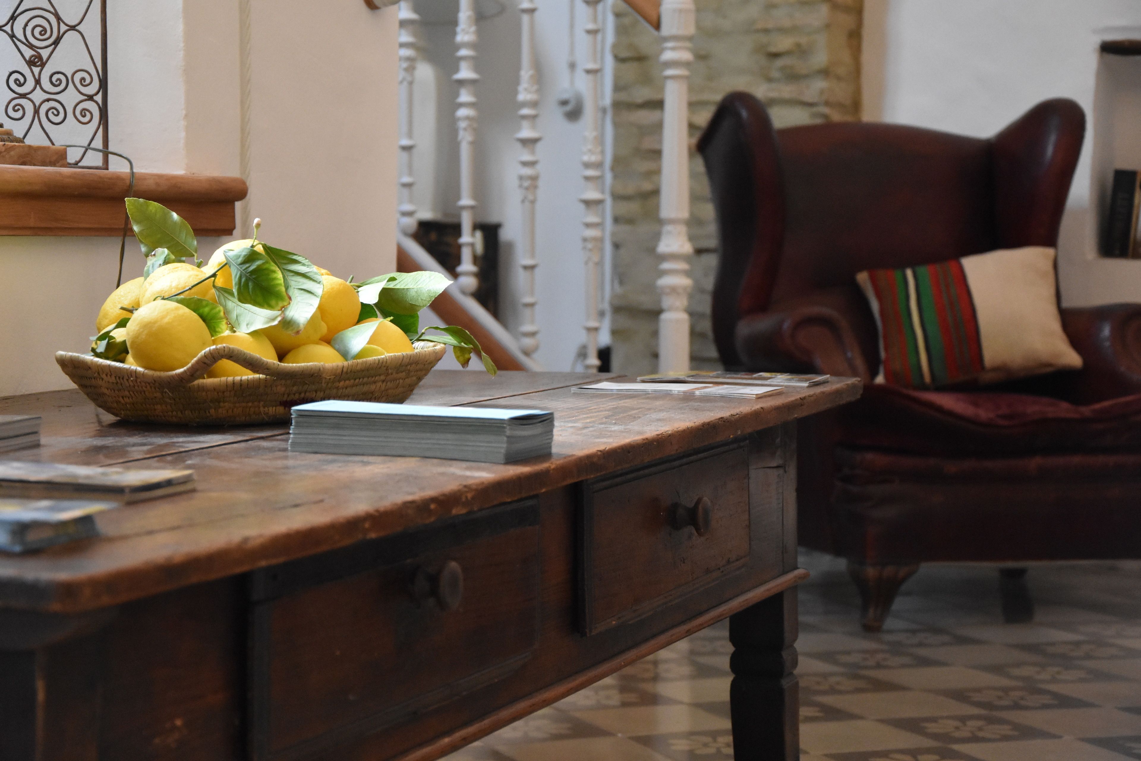 A wooden desk with a basket of lemons and a stack of papers.