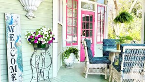 A porch with wicker furniture, a welcome sign, and a potted plant. - Peacock Place (Eastman)