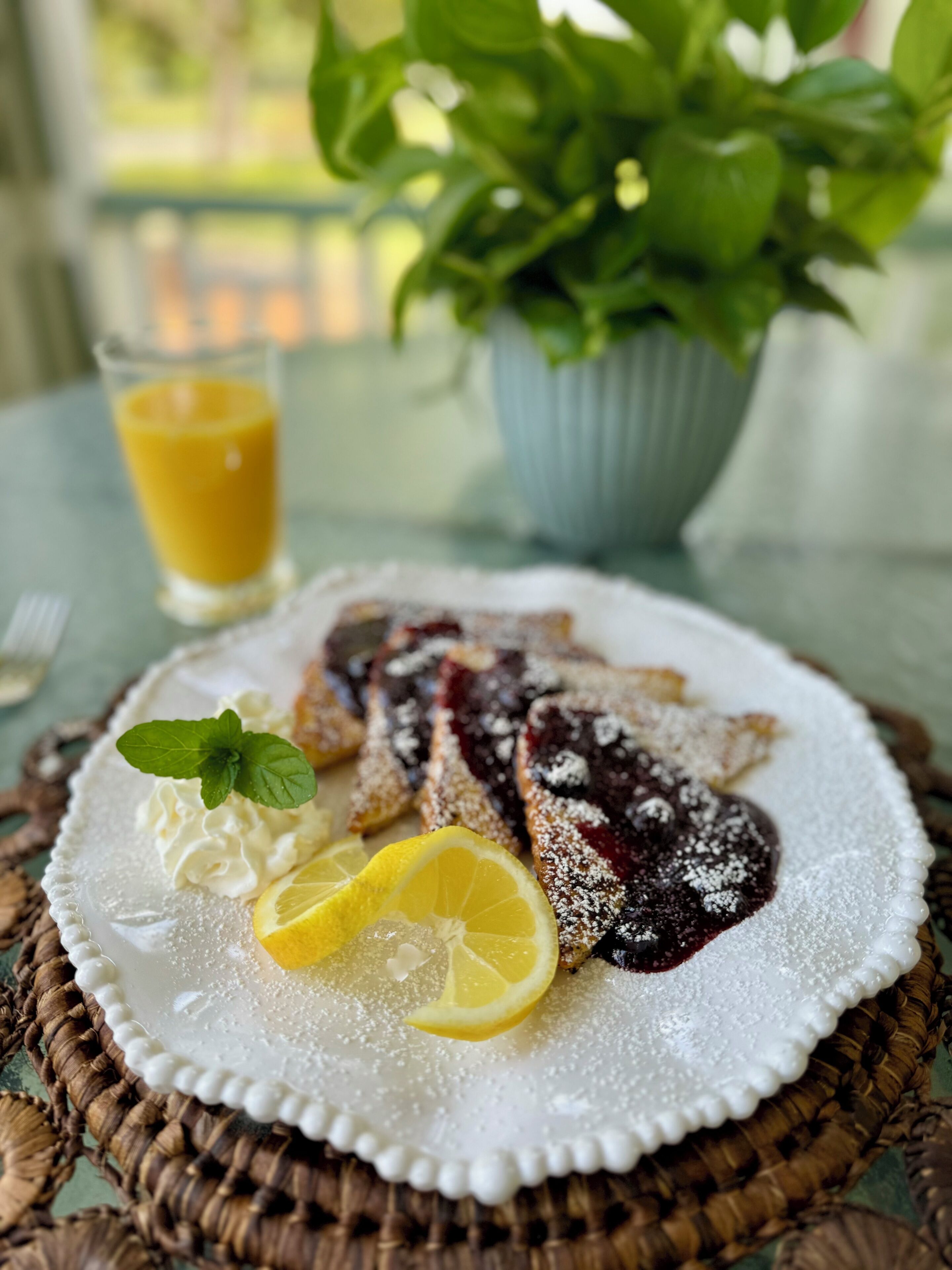 Une assiette de nourriture, ornée d’une tranche de citron et de quelques feuilles de menthe, posée sur un set de table en fibres tressées.