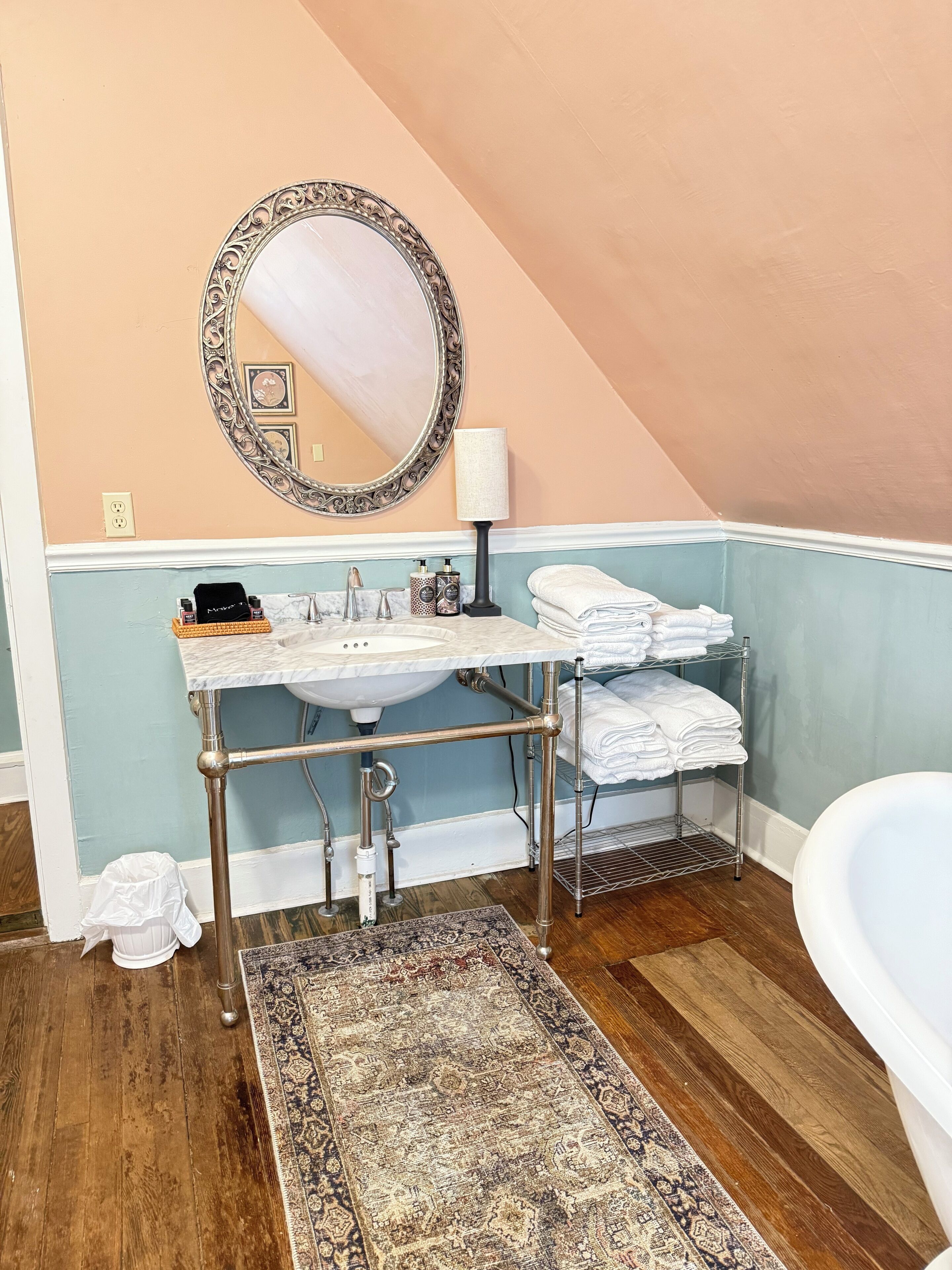 A bathroom with a vanity, sink, mirror, towel rack, and a large rug.