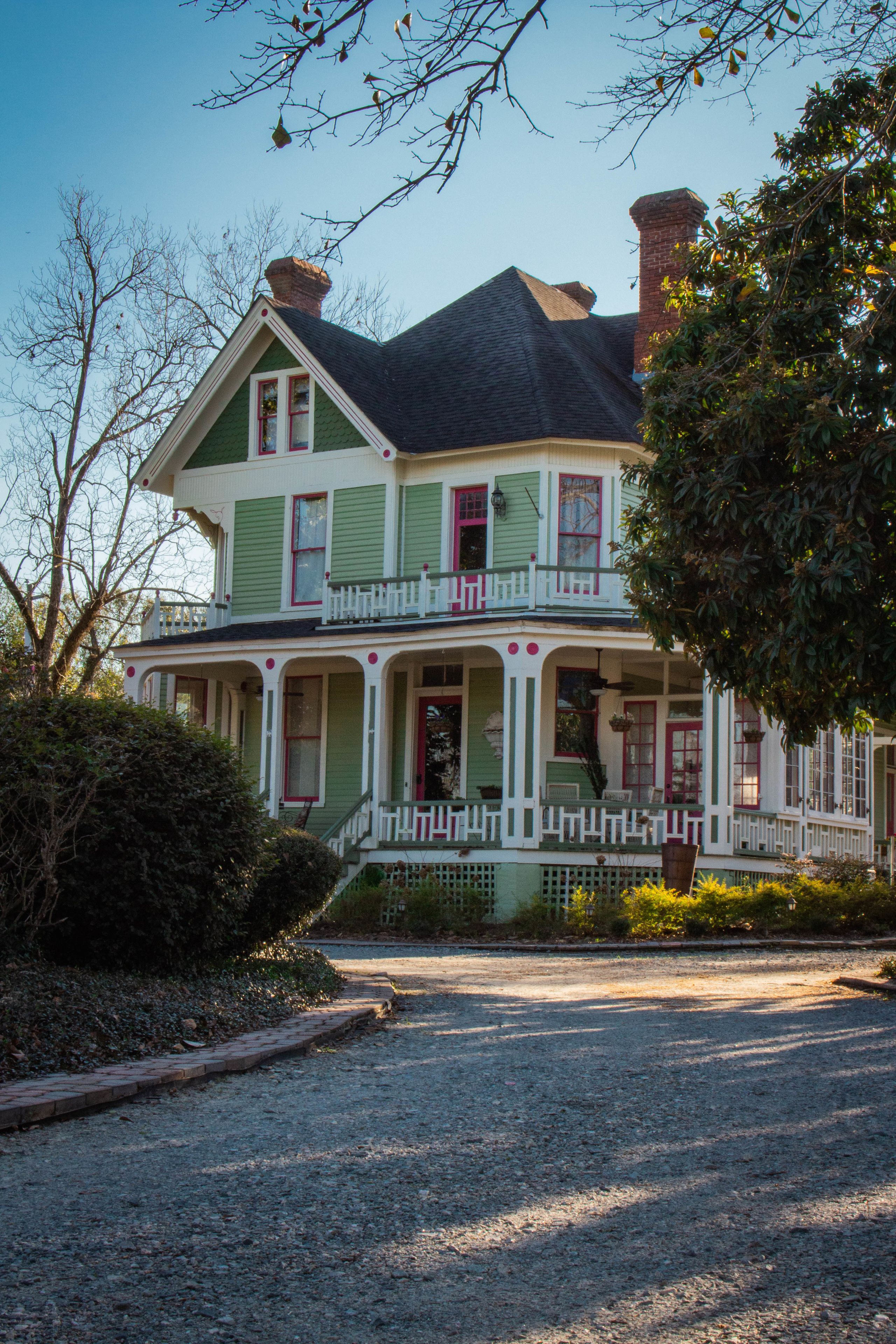 A two-story house with a front porch, a chimney, and a small garden area.