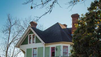 A two-story house with a front porch, a chimney, and a small garden area.