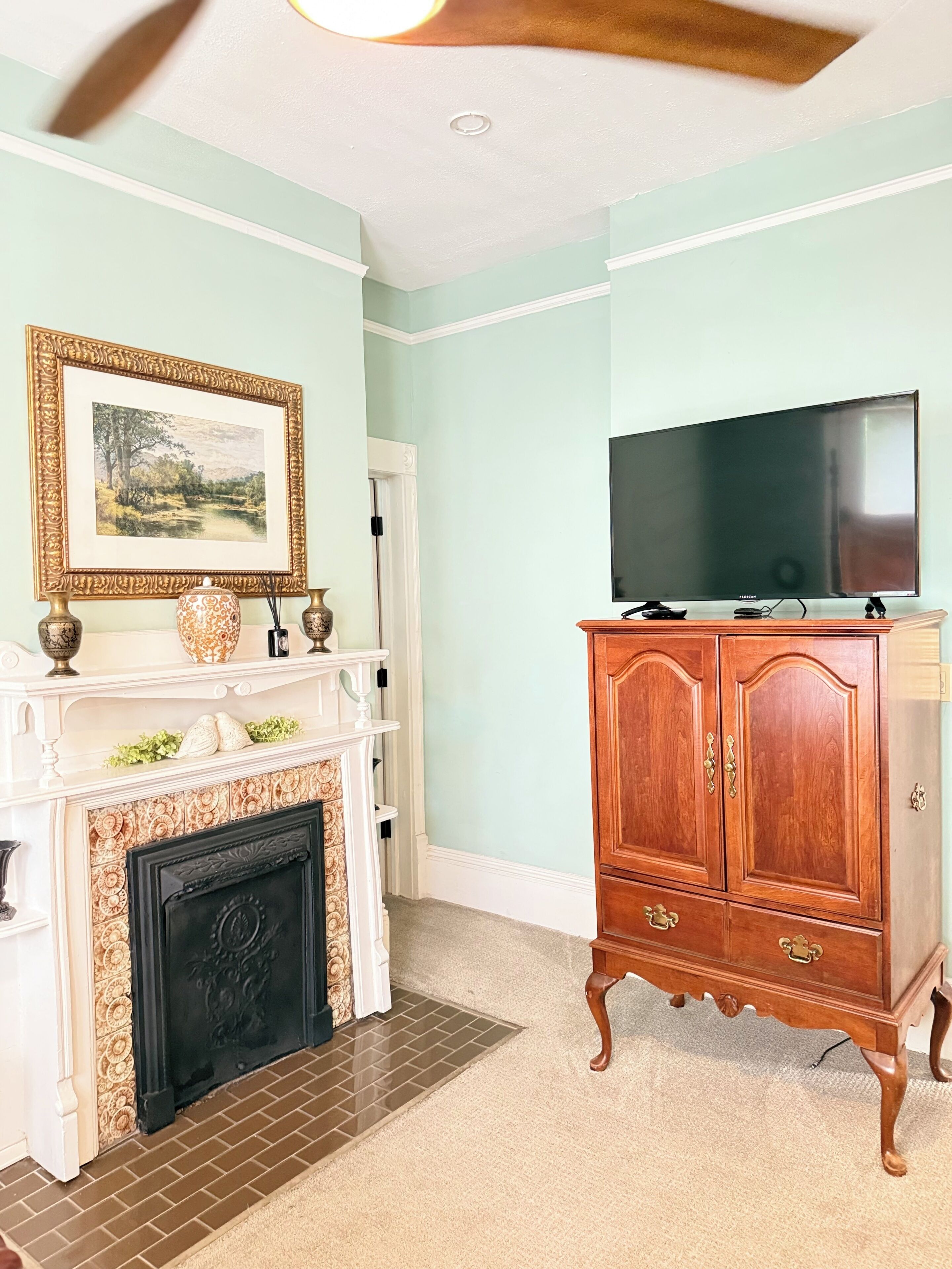 A room with a fireplace, a television, and a wooden cabinet.