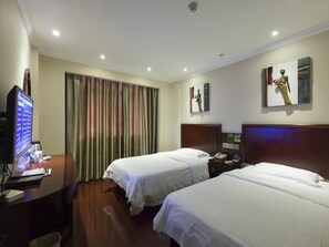 A hotel room with two beds, a desk with a computer, and a television.