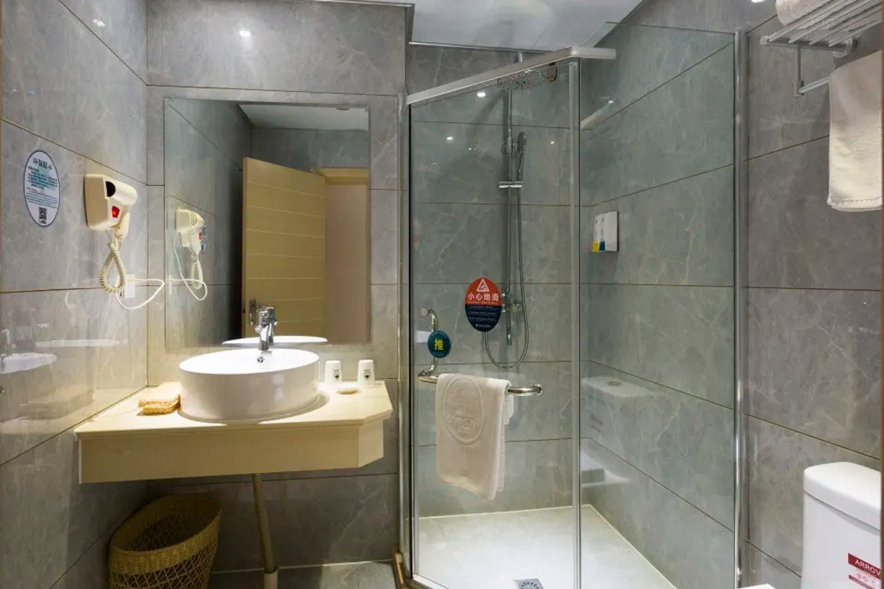A modern bathroom with a glass-enclosed shower, a sink with a mirror, and a towel rack.