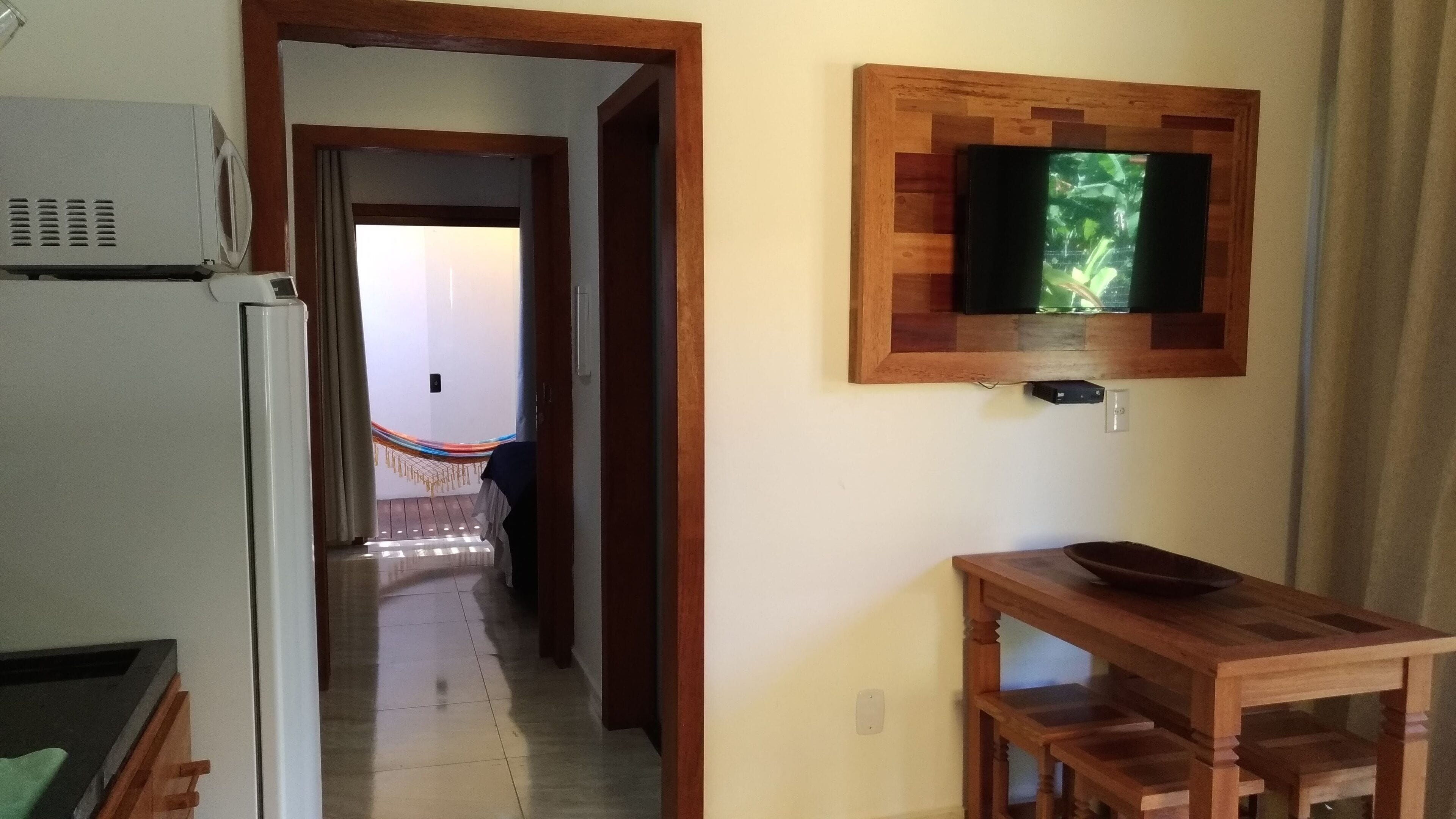 A hallway with a wooden table and a television mounted on the wall.