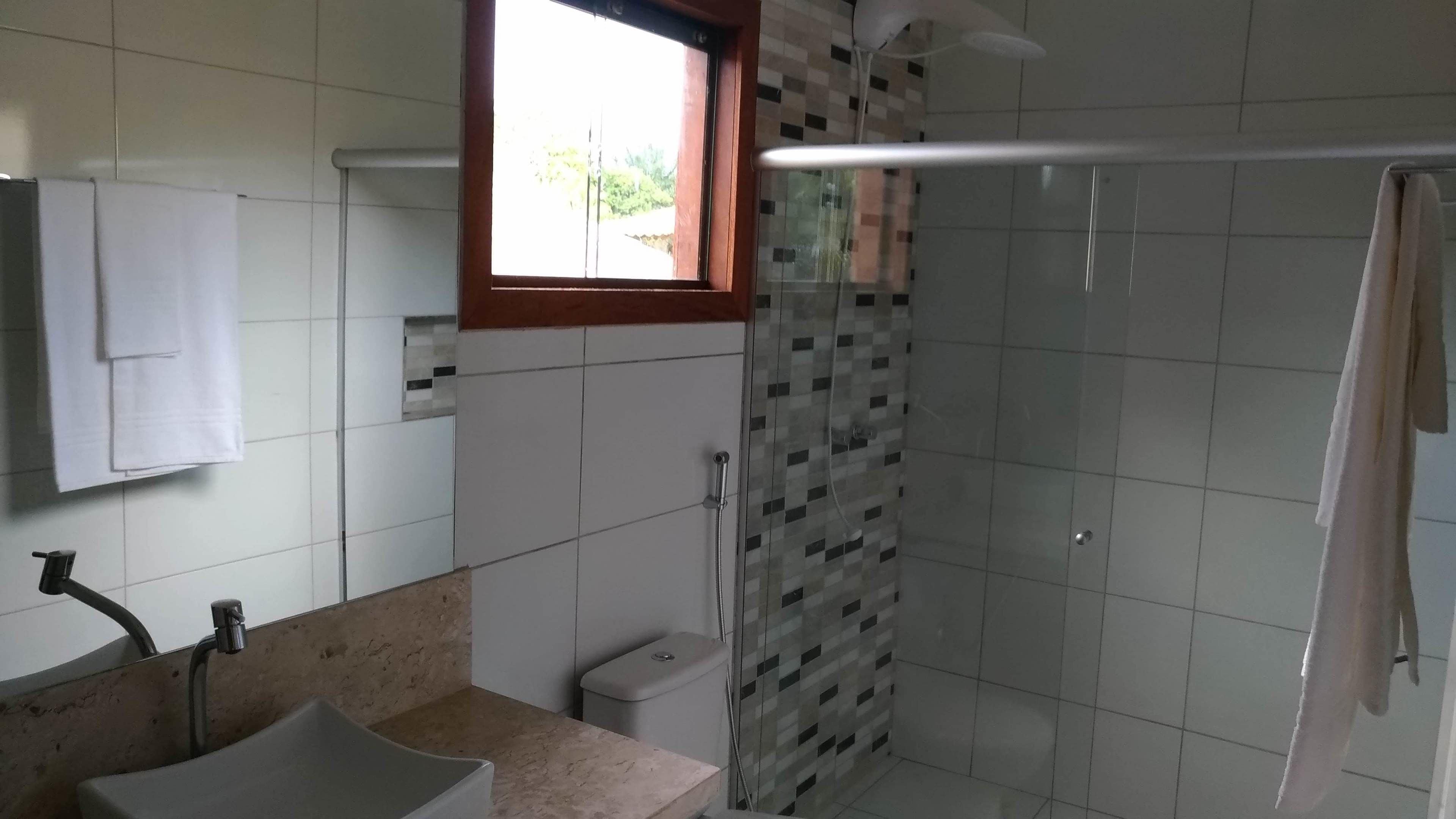 Un baño con lavamanos, espejo, toallero, ducha e inodoro.