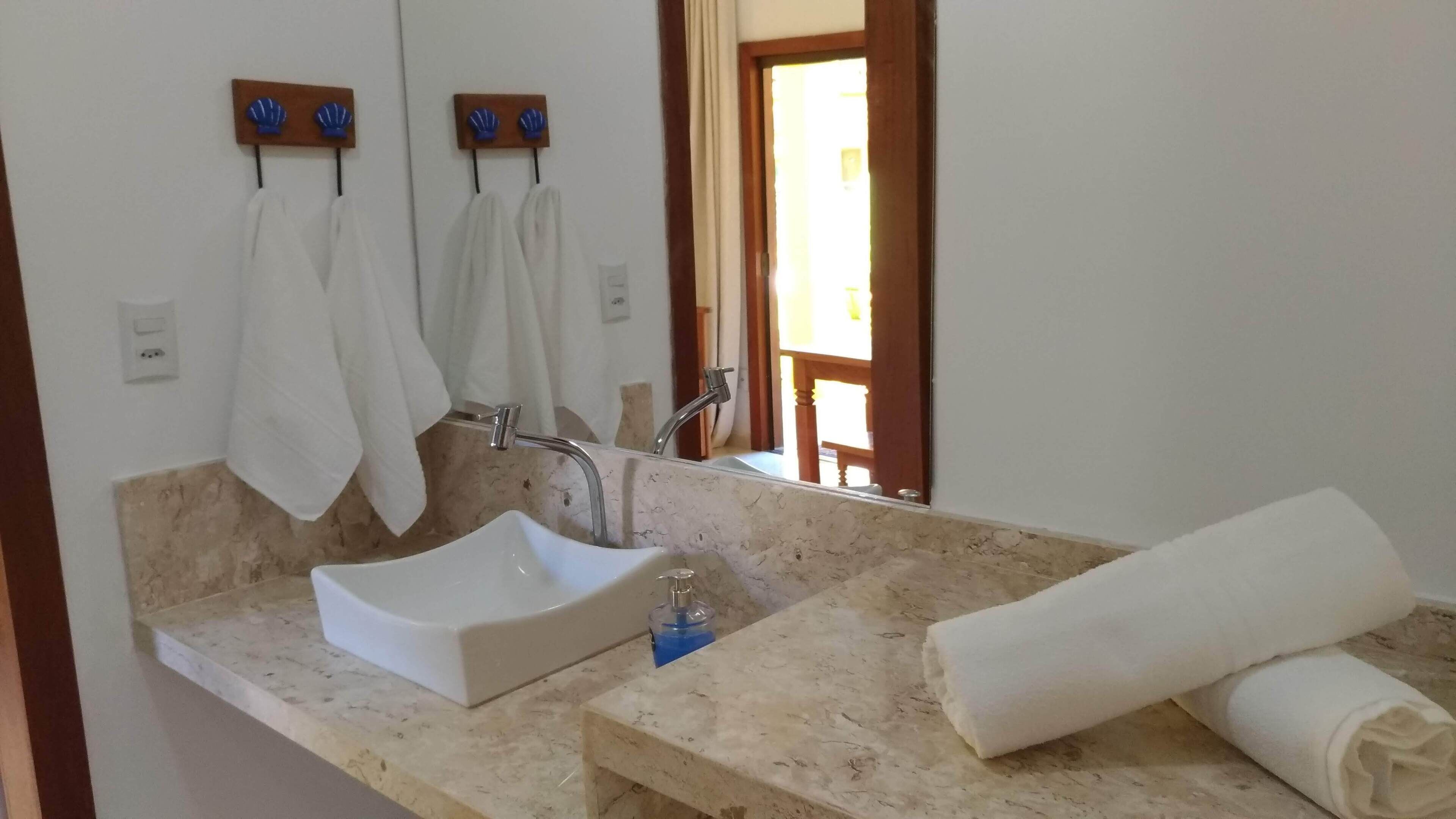 A bathroom with a white sink, a mirror, and two towels hanging on hooks.