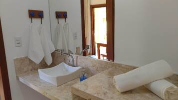 A bathroom with a white sink, a mirror, and two towels hanging on hooks.