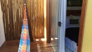 A room with a bed, a wooden floor, and a bamboo partition. - Conchas do Mar Residence (Itacaré)