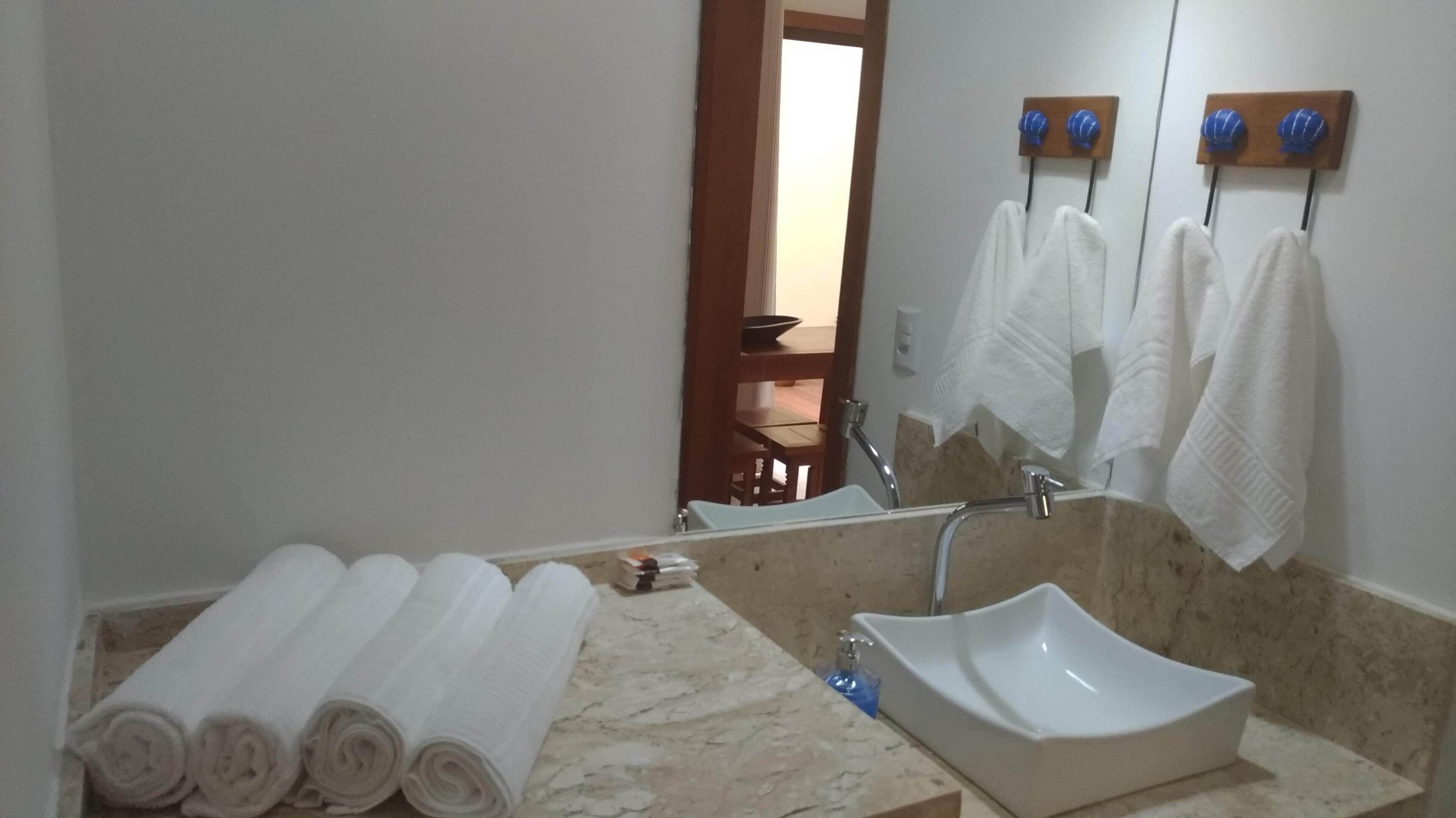 Une salle de bain avec un lavabo en marbre, un miroir et des serviettes rangées sur un porte-serviettes.