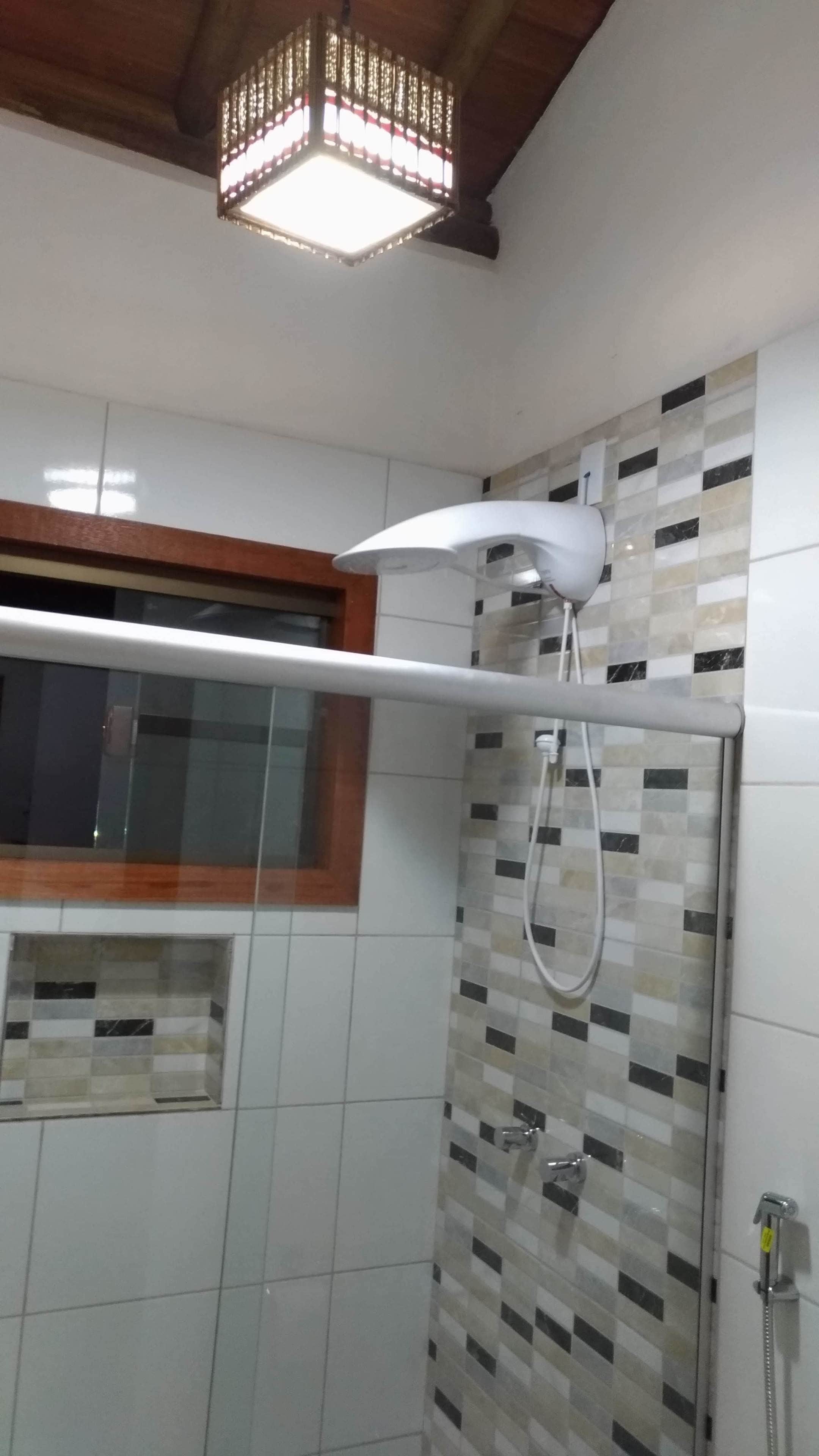 A modern bathroom with a shower, tiled walls, and a hanging light fixture.
