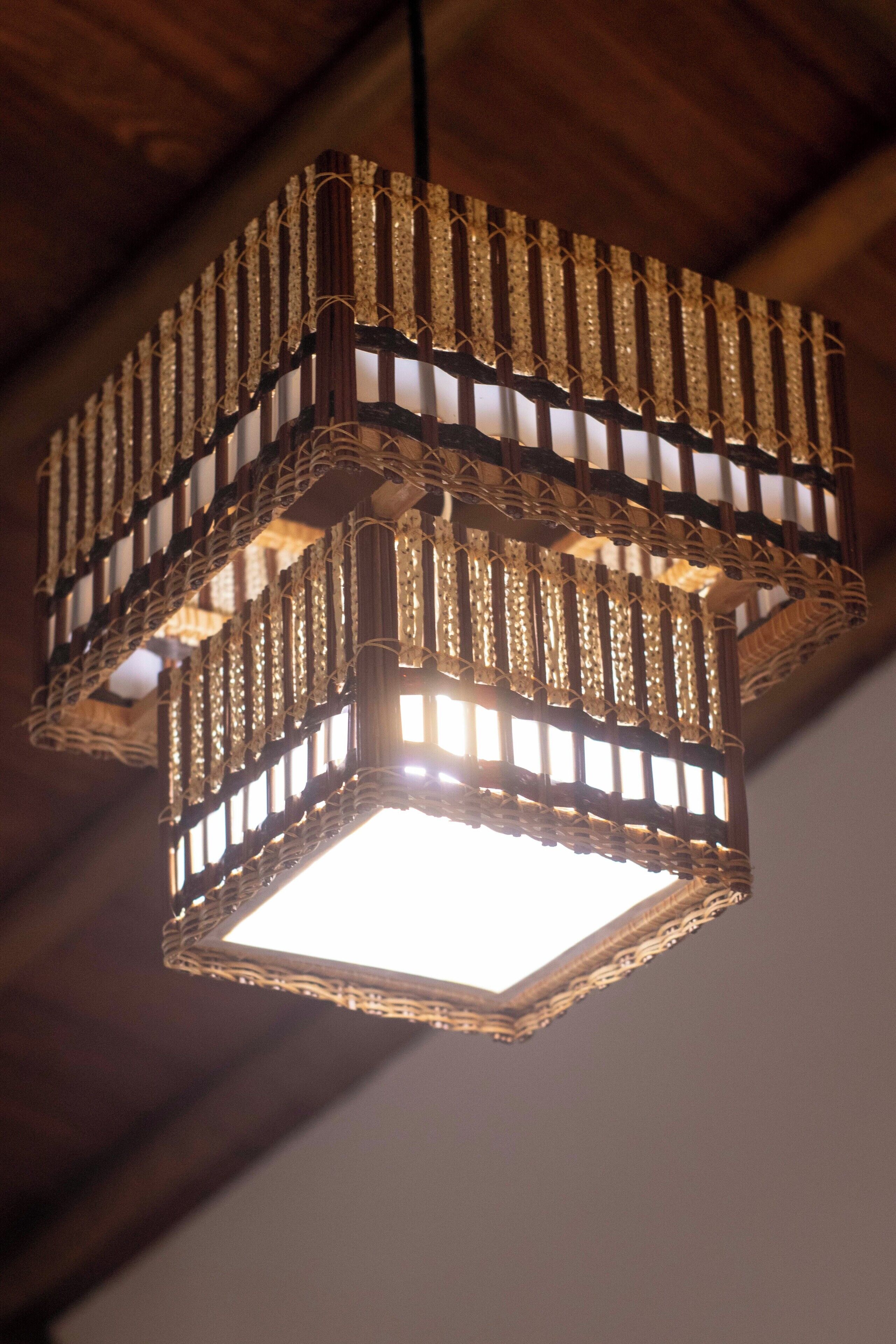 A hanging light fixture with a geometric design and a central illuminated panel.