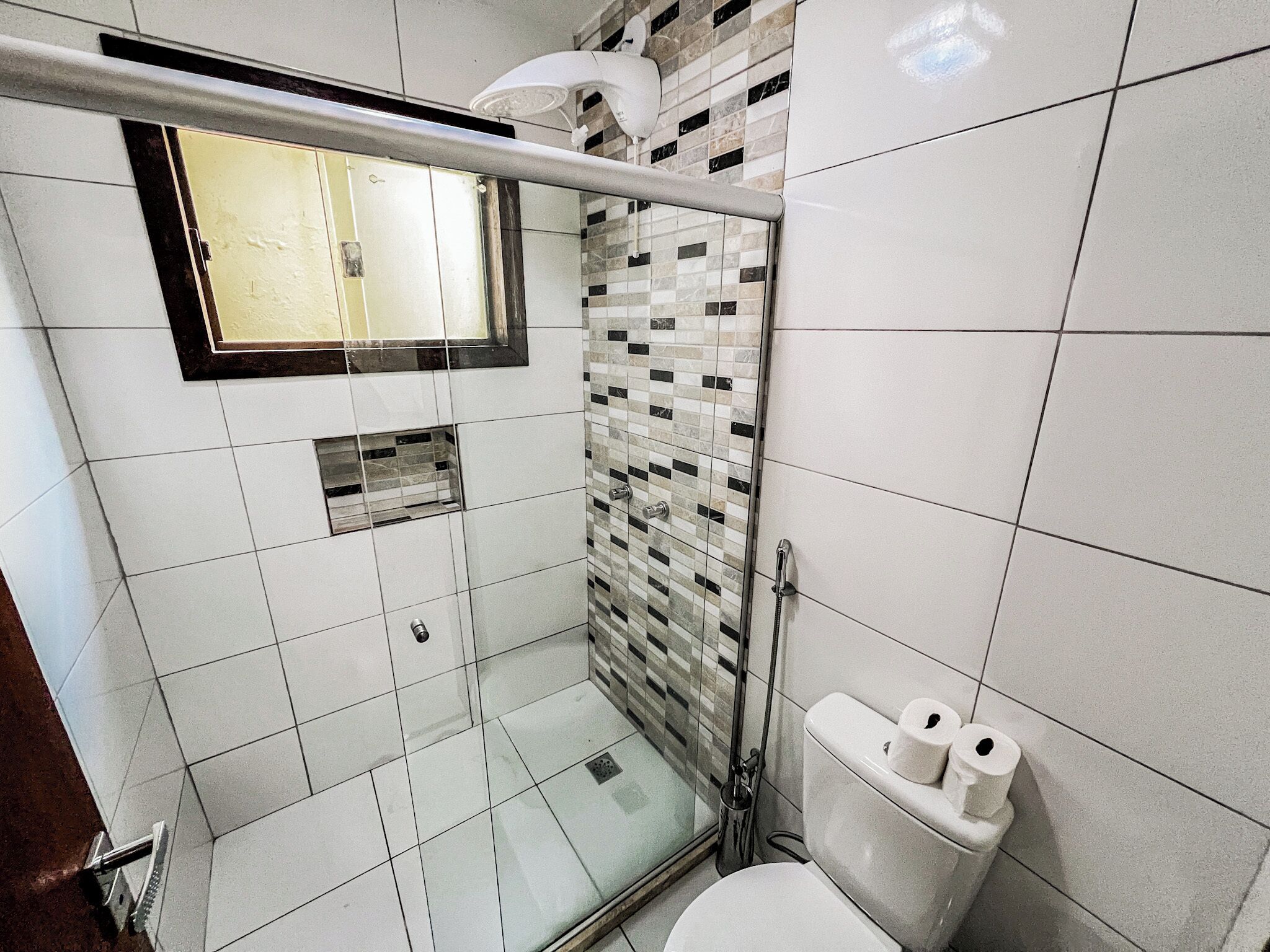 A modern bathroom with a glass-enclosed shower, a toilet, and a sink.