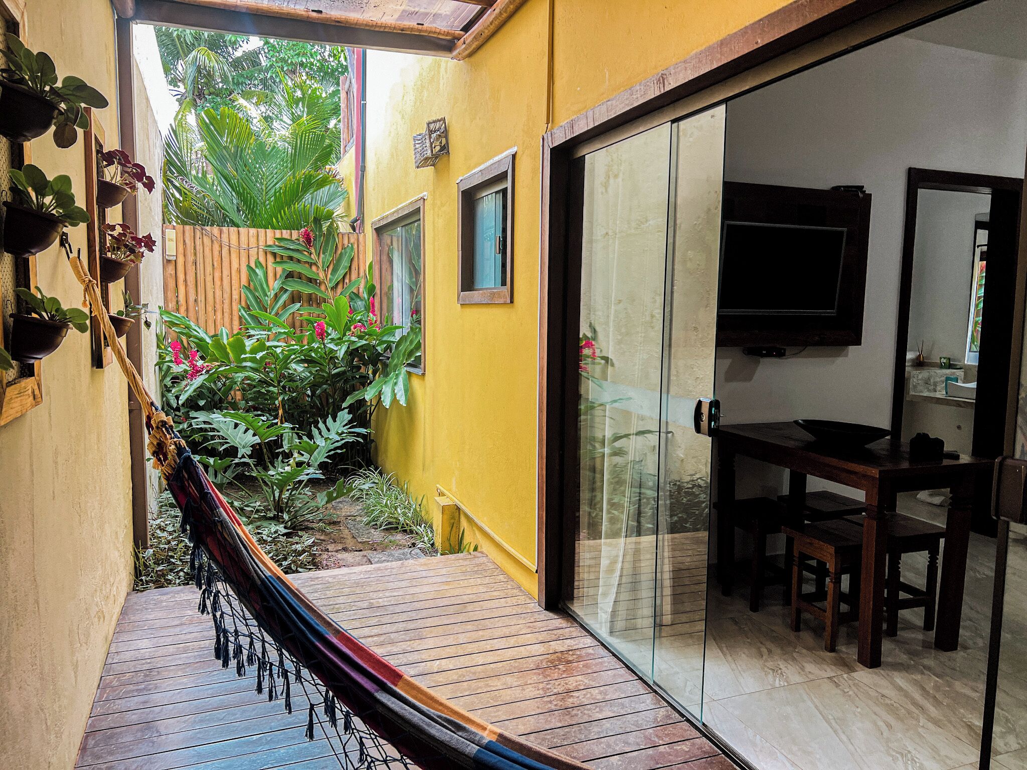 A room with a sliding glass door leading to a patio area with a hammock and potted plants.
