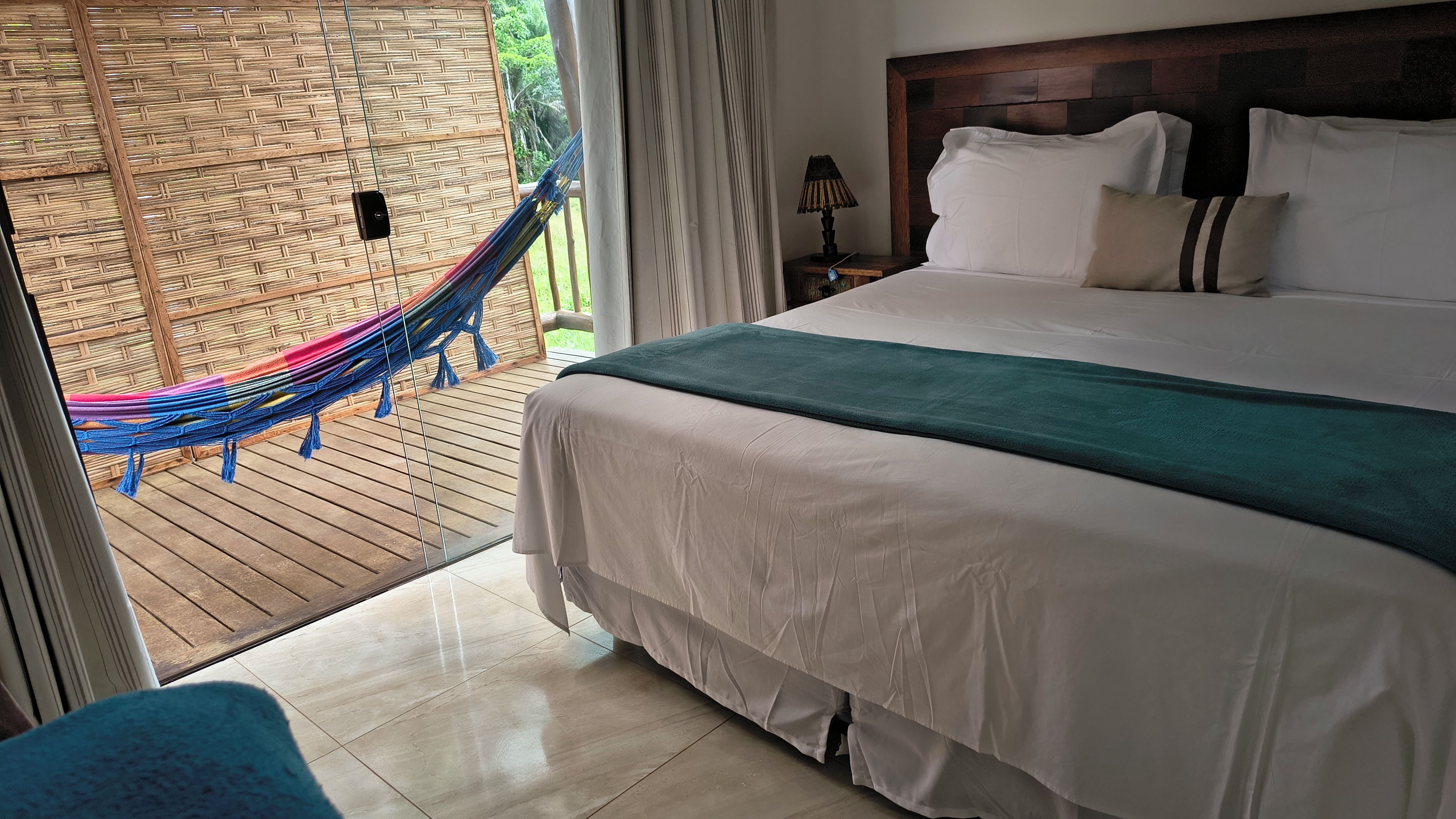 Ein Schlafzimmer mit einem Bett, einer Hängematte und Blick ins Freie.
