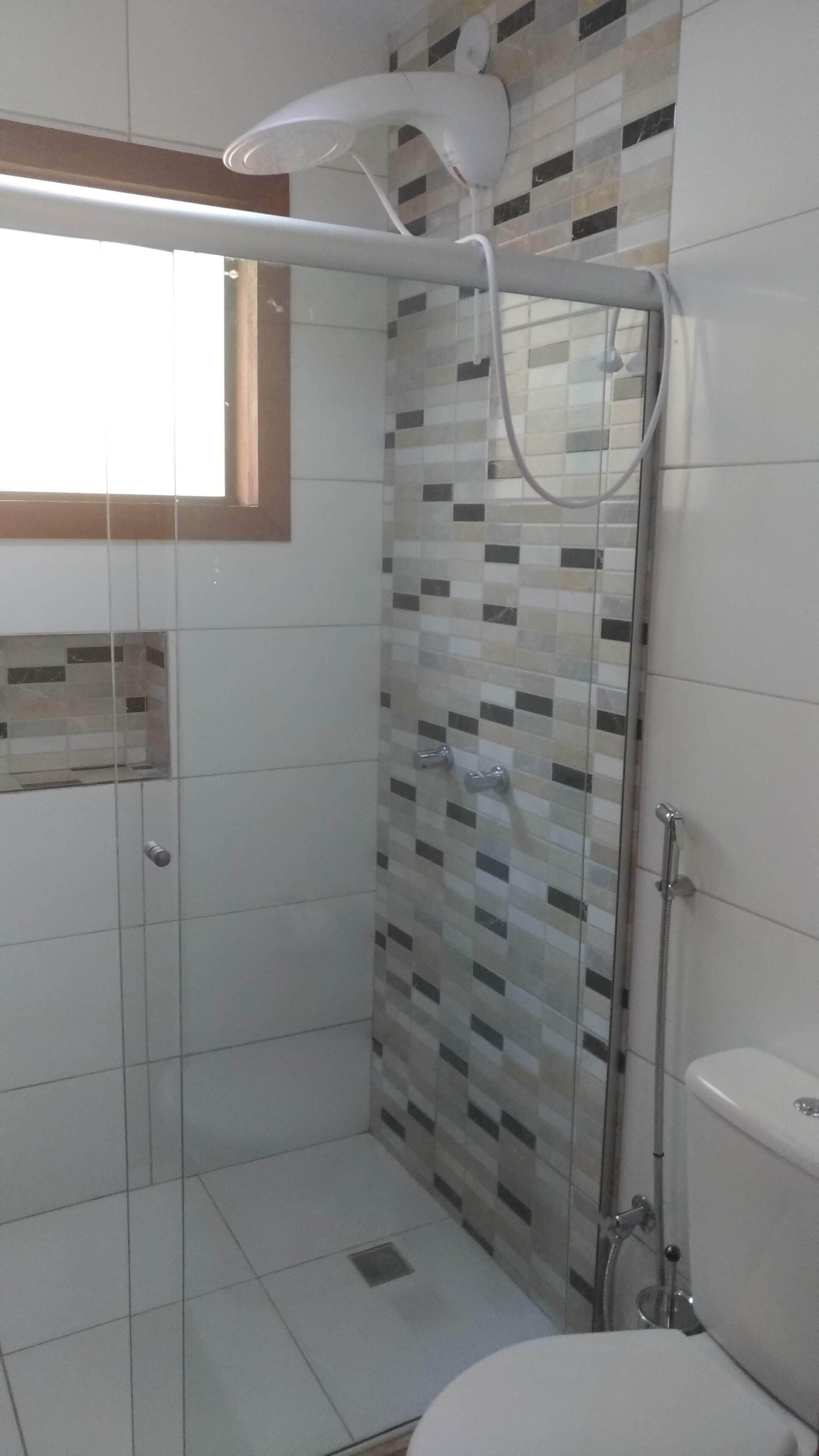 A bathroom with a shower, toilet, and a window.