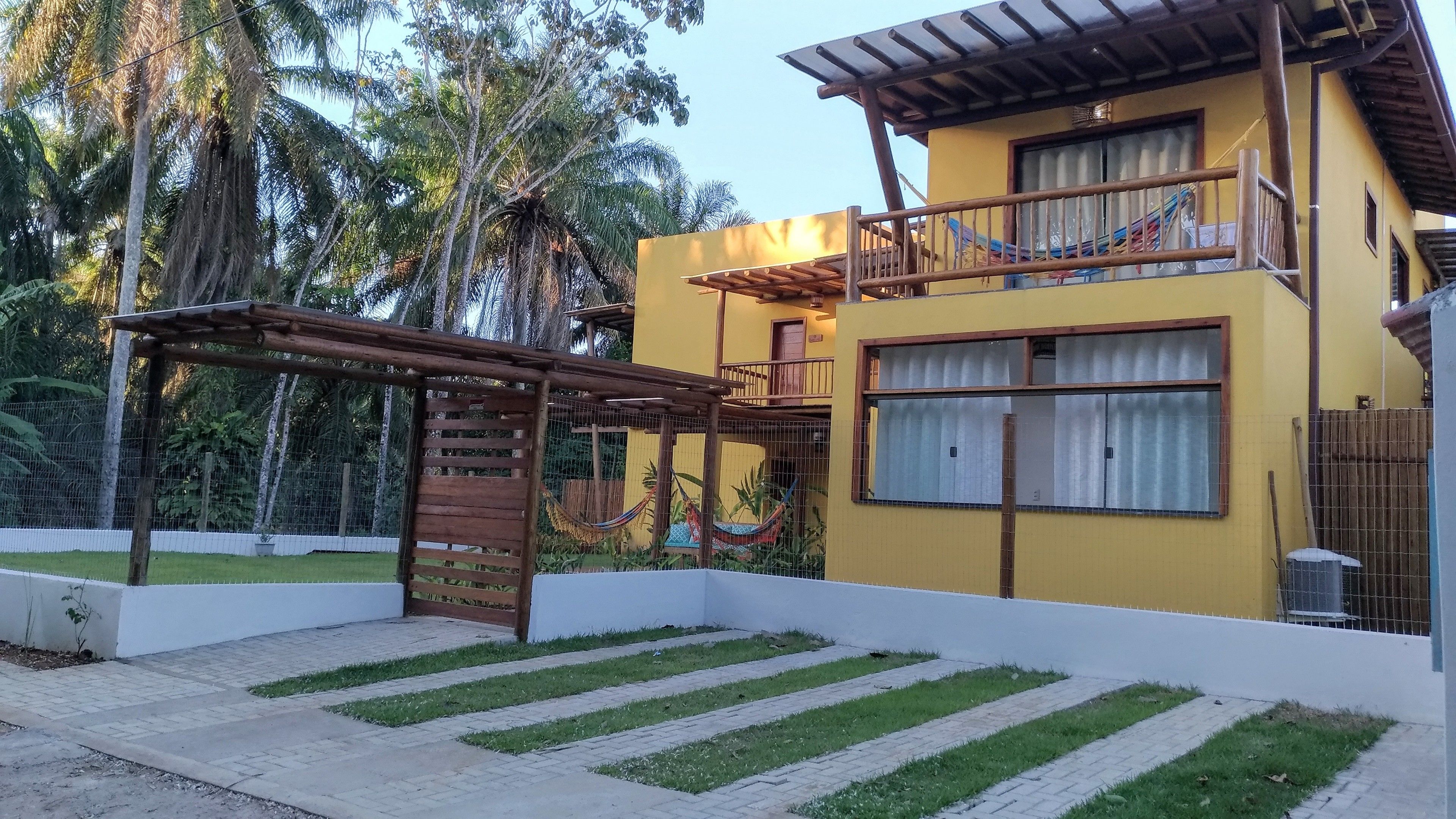 Un bâtiment à deux étages doté d’un balcon, d’un hamac et d’une zone clôturée avec de l’herbe.